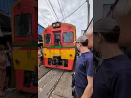 Поезд едет через оживленный рынок в Таиланде