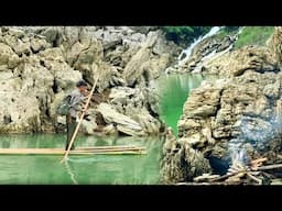 Survive and set up camp under a large rock catch snails to eat and spend the night by the river bank