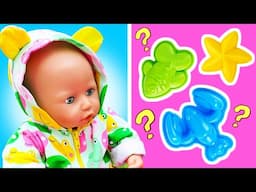 Baby Annabell doll makes sand dinos with colorful dinosaur molds on a playground.