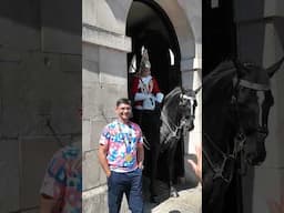 A man shows his medal in front of the Horse guard