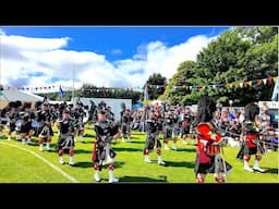 Lonach Highlanders march out of Games field led by Pipe Band at 2024 Lonach Gathering in Scotland